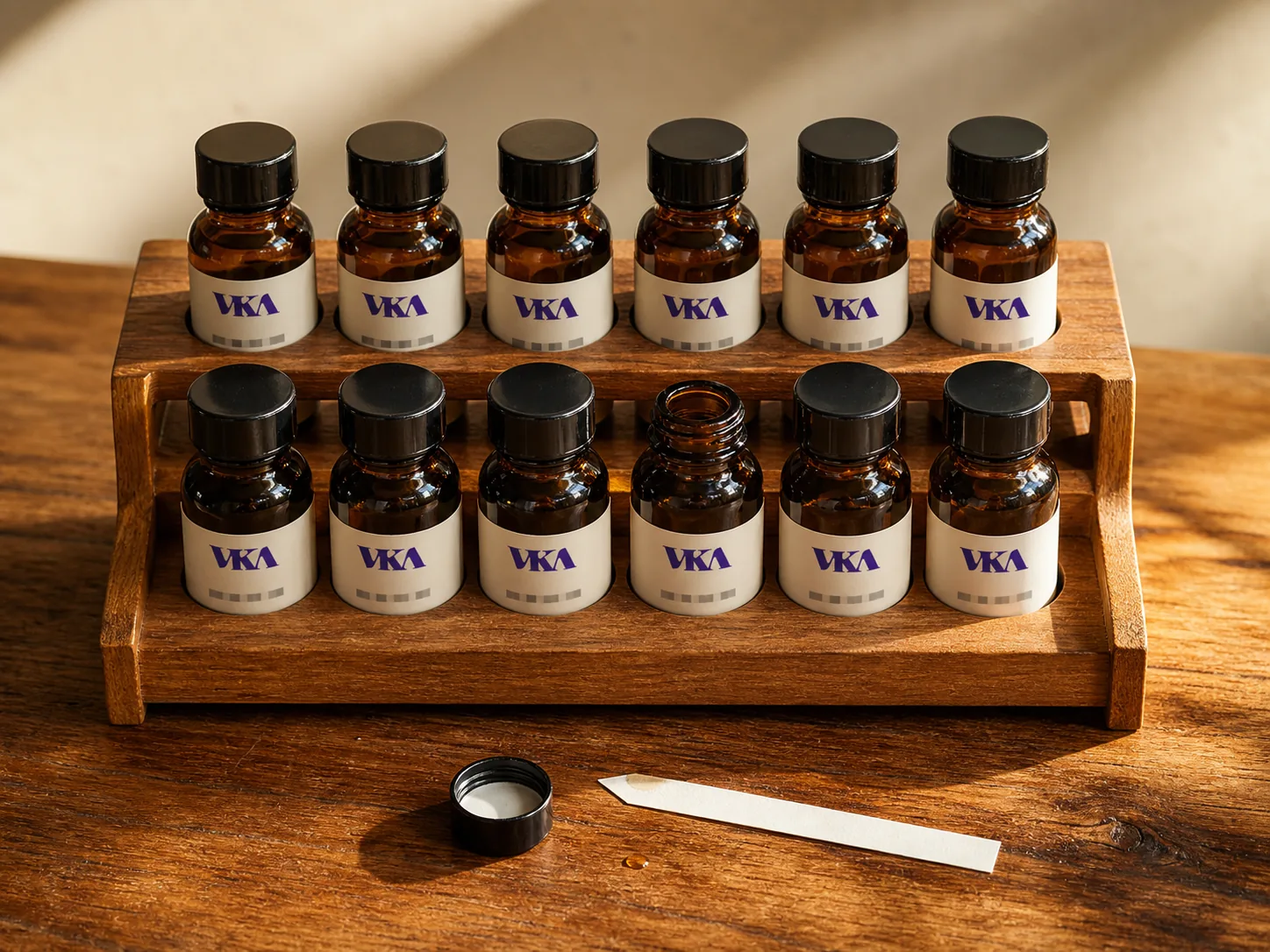 A rack of twelve amber sample bottles on the VKA Australia bench, one uncapped beside a smelling strip.